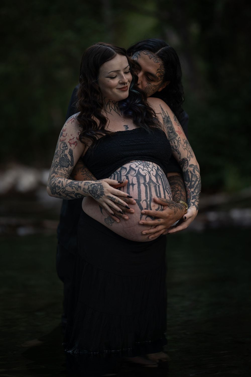 Intimate maternity portrait session by water featuring artistic tattoo details.