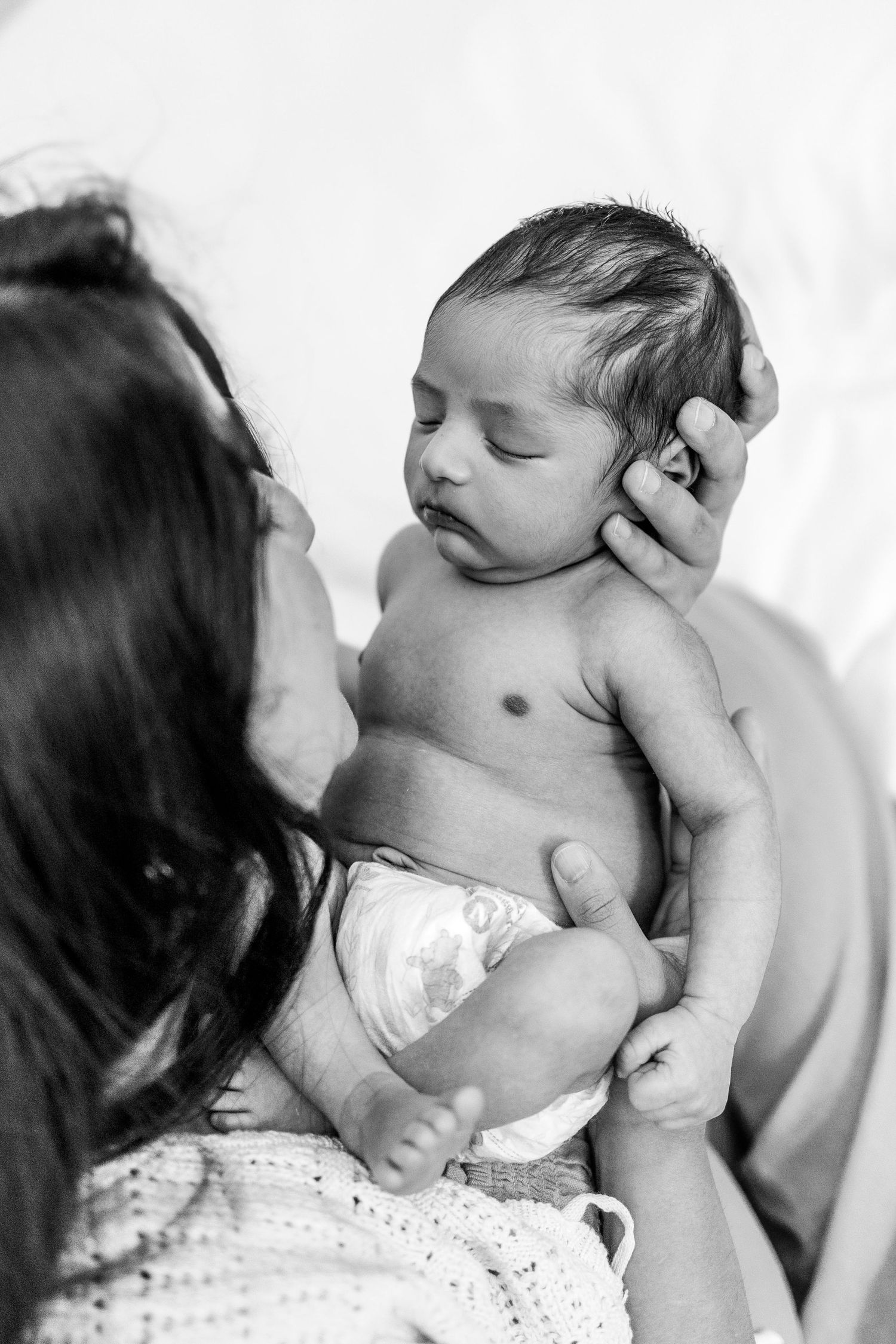 Black and white photo of tender moment between mother and infant.