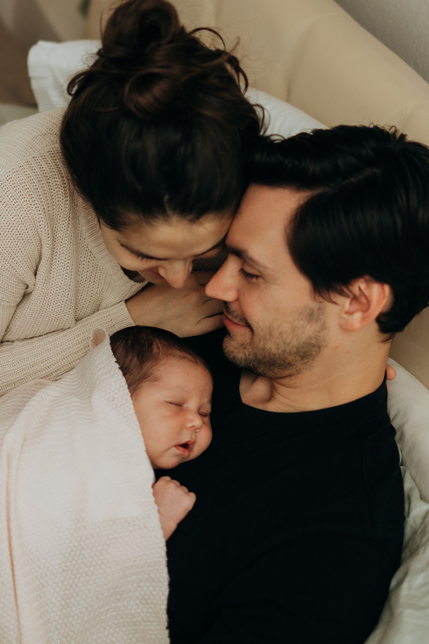 Intimate family moment with sleeping newborn in cozy knit sweaters.