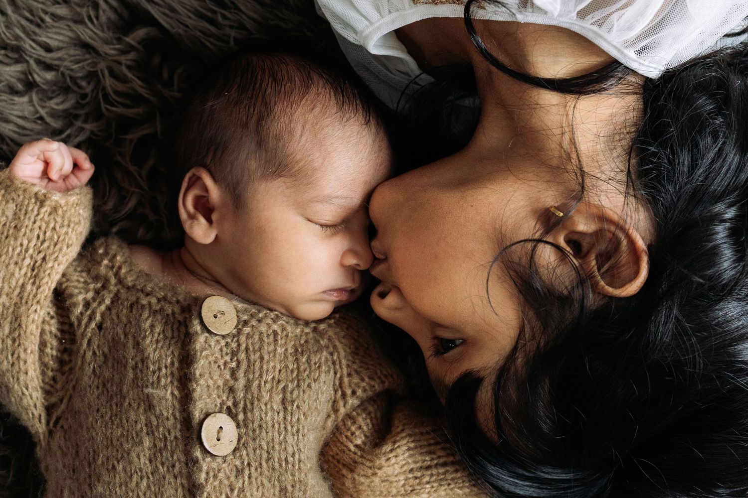 Tender moment with sleeping baby wearing cozy knit sweater.