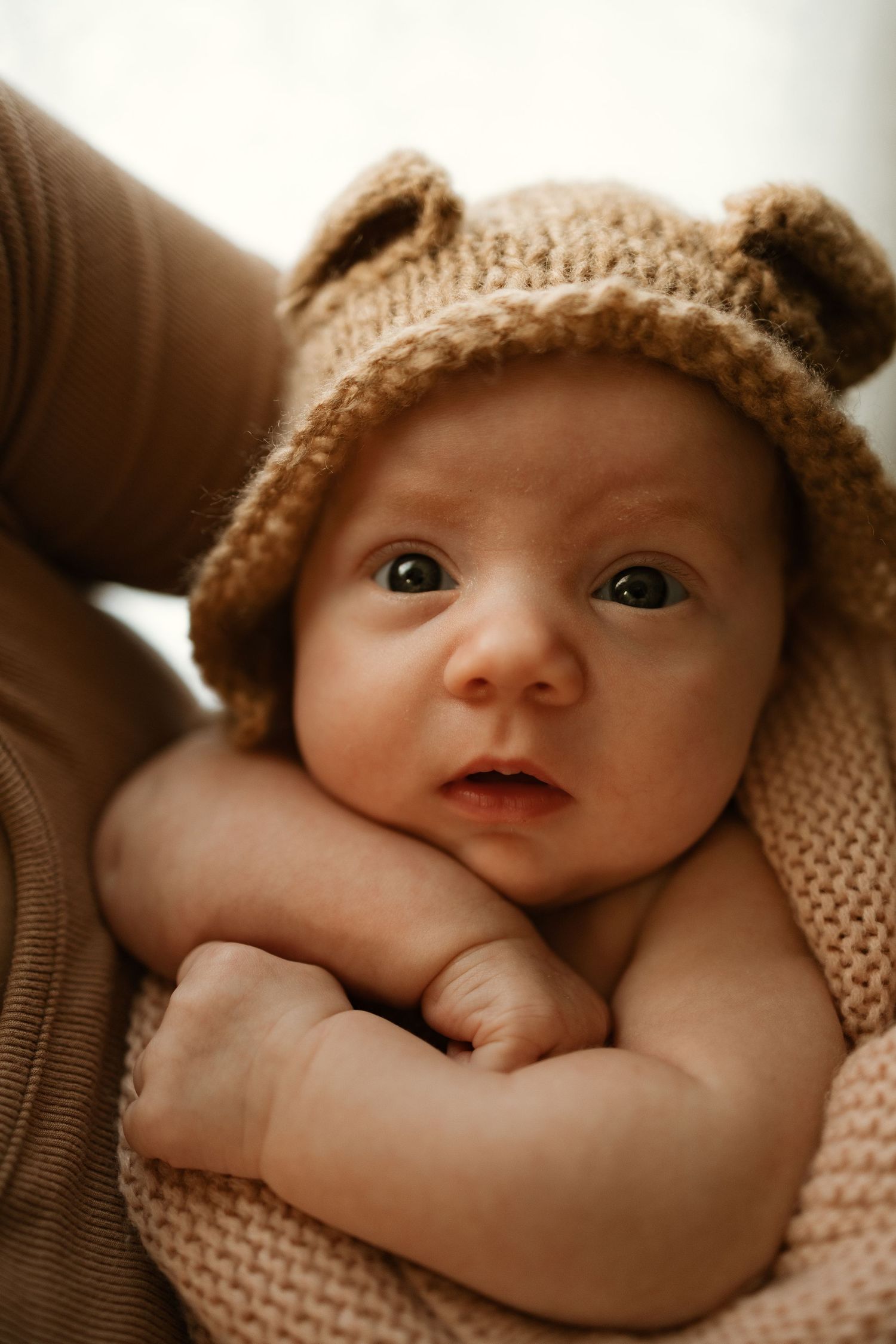 A series of sepia-toned photos showing a small baby wearing a knit hat while lying down.