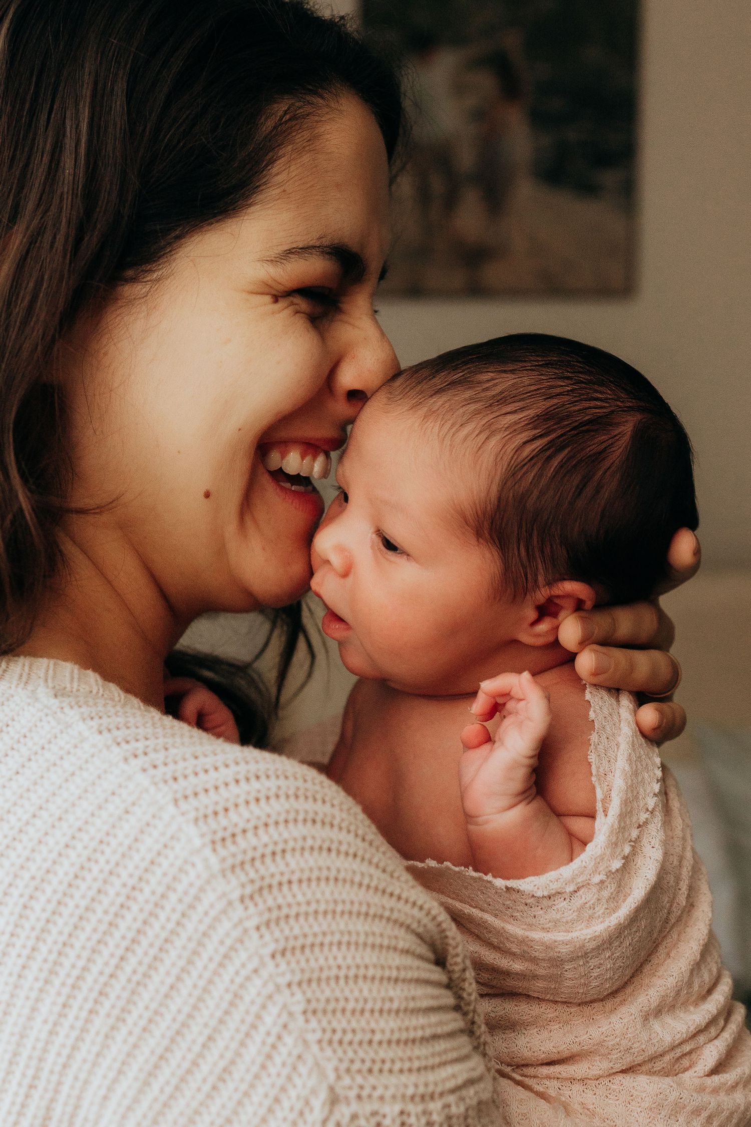 Intimate mother and baby bonding moment in warm indoor lighting.