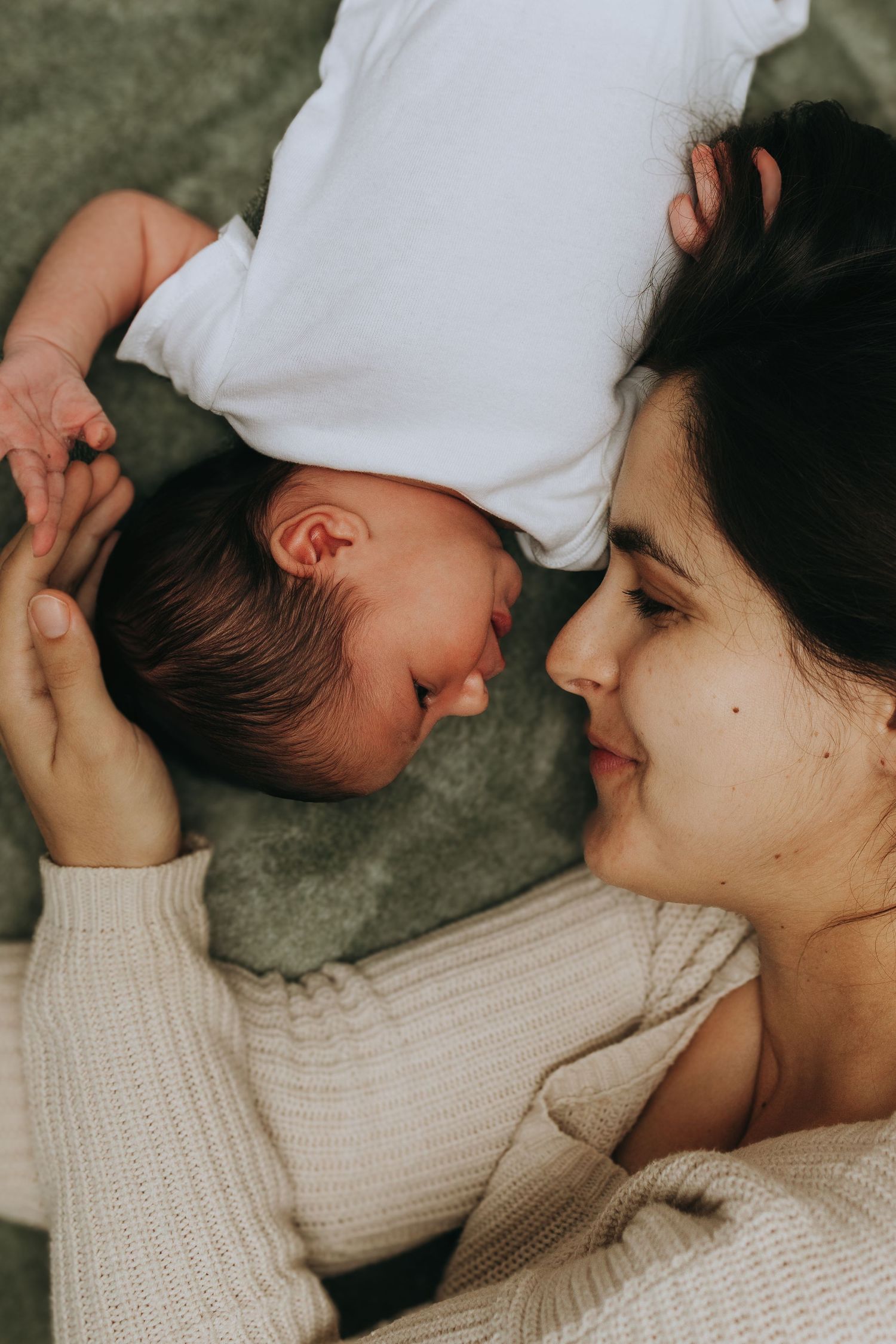 Gentle bonding moment between parent and infant on cozy grey background.