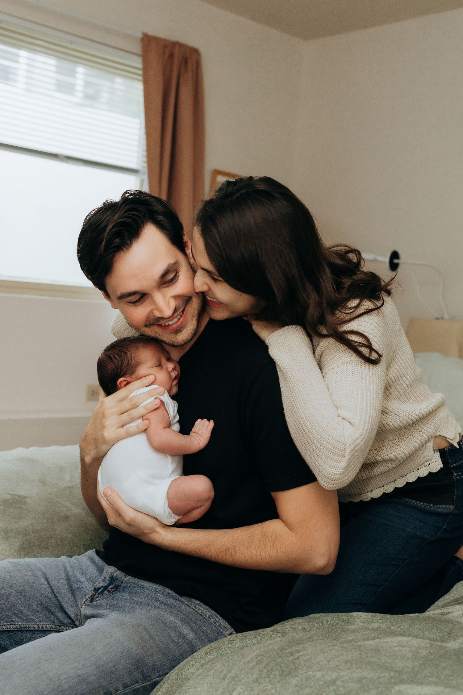 Candid family moments captured on bed showing joyful interaction with baby.