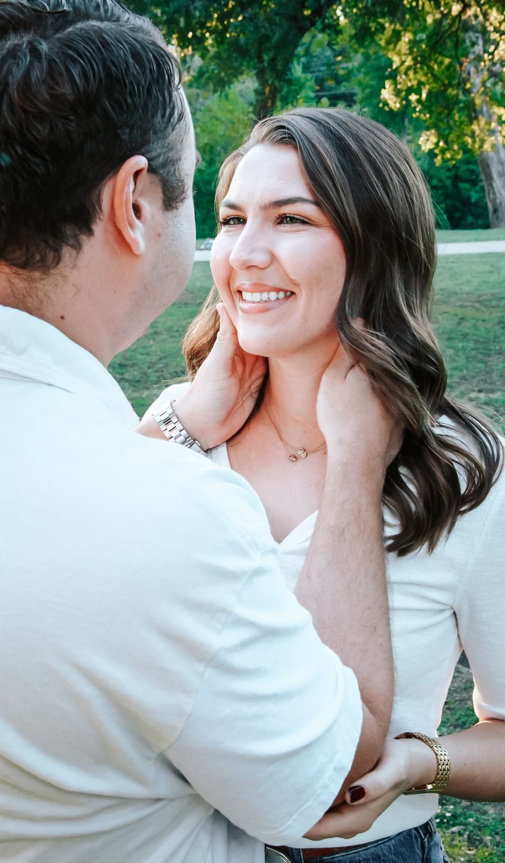 Man tenderly holding womans face as she smiles warmly during an outdoor engagement session.