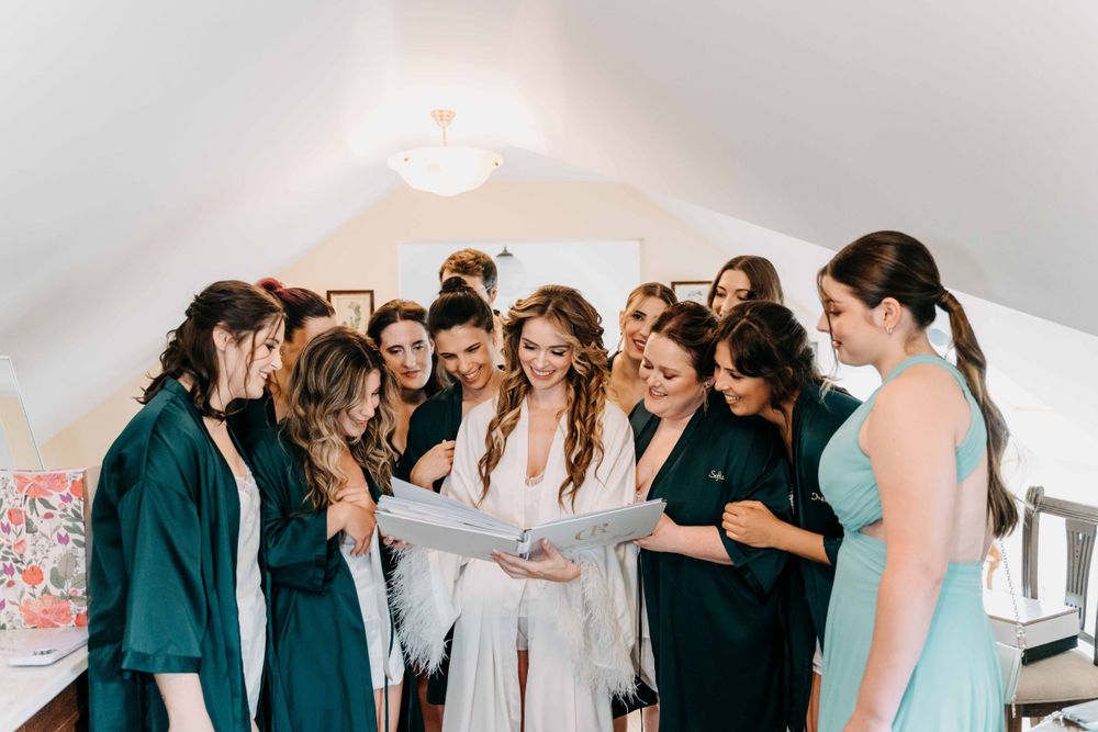 A group in matching robes and dresses huddle together during a special celebration event in a white venue space.