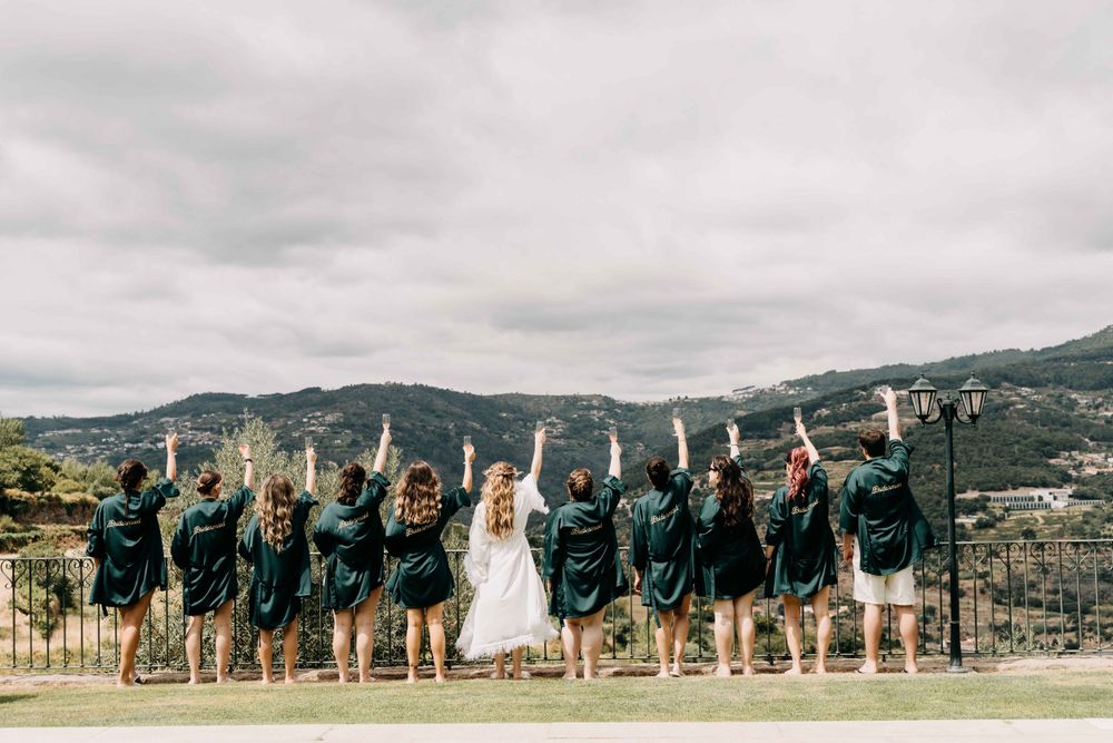 Bridesmaids in matching navy dresses pose with bride on a scenic overlook with mountains in the background.