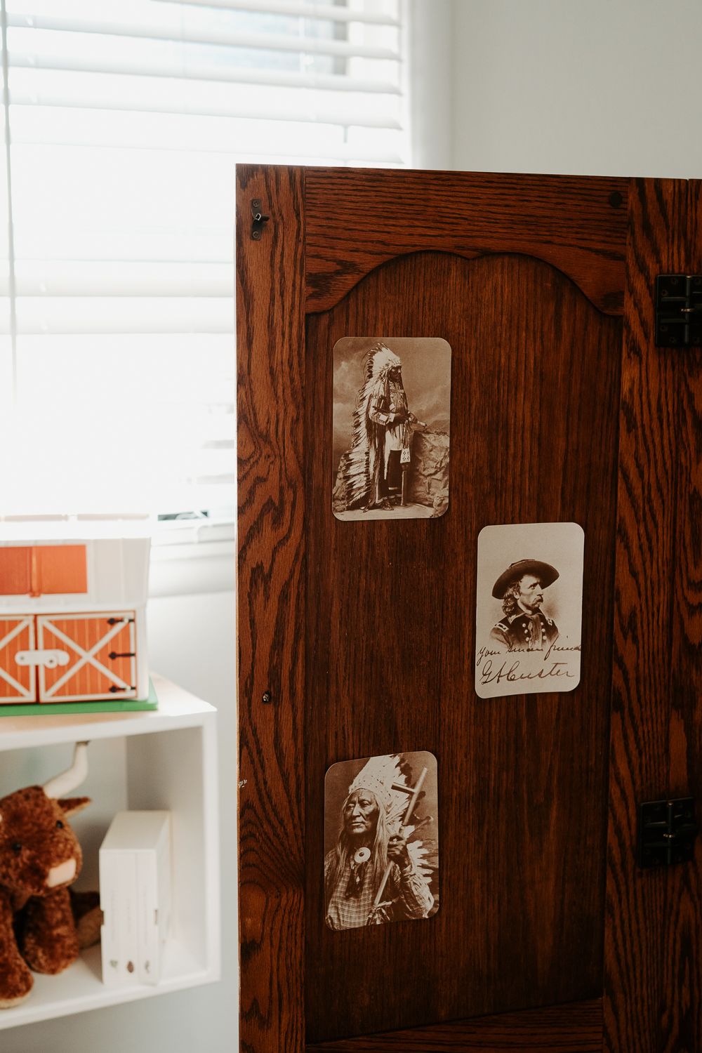 Vintage photographs displayed on dark wooden wall near white shelving.