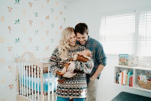A nursery room with floral wallpaper, white crib, and blue accents creates a cozy baby space.