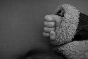 Black and white image showing tiny fingers against soft textured fabric.