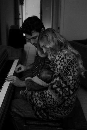 Dark moody photograph of couple at piano in black and white.