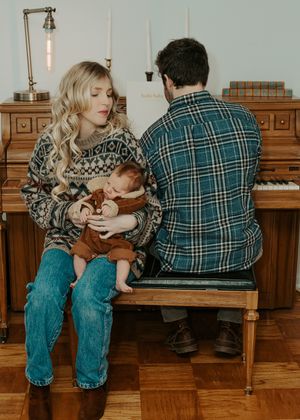 Family sitting together on wooden bench near vintage piano.