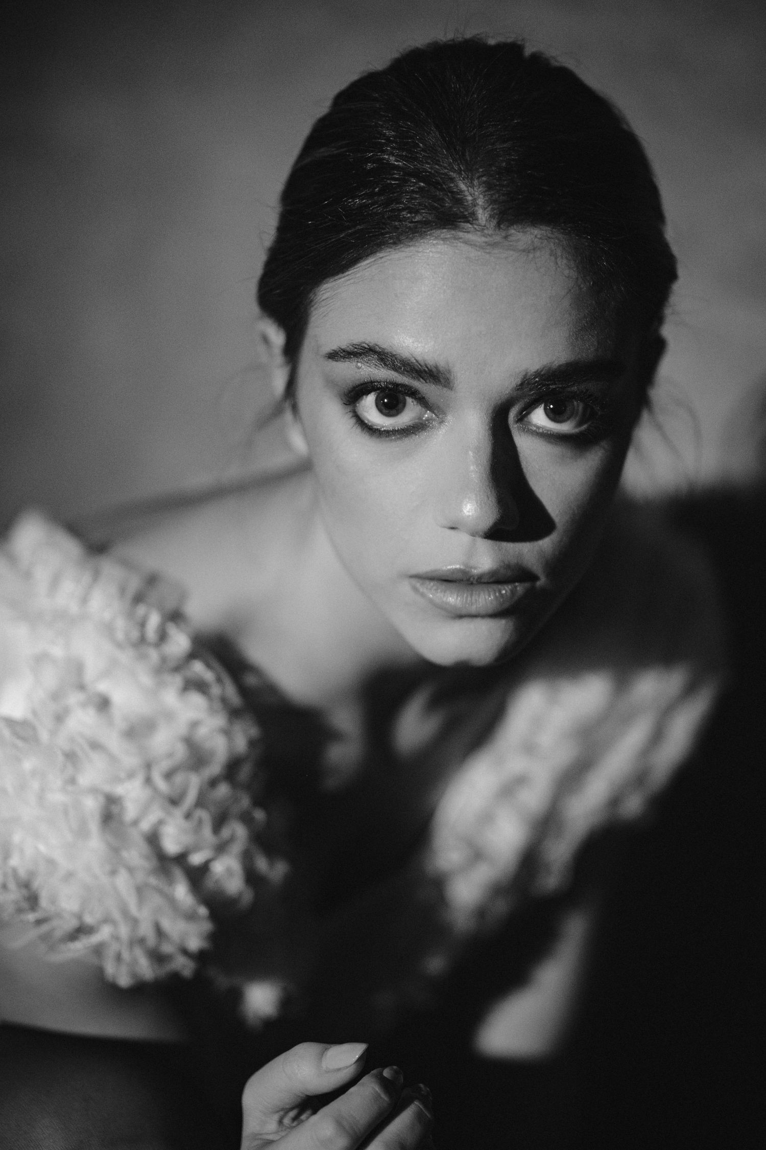 Close-up black and white portrait with strong shadows and intense gaze.