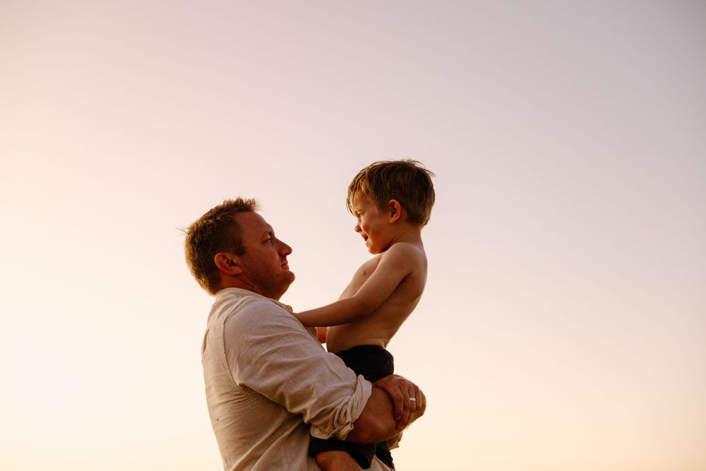 Tender moment silhouetted against a pink sunset sky in an emotional embrace.