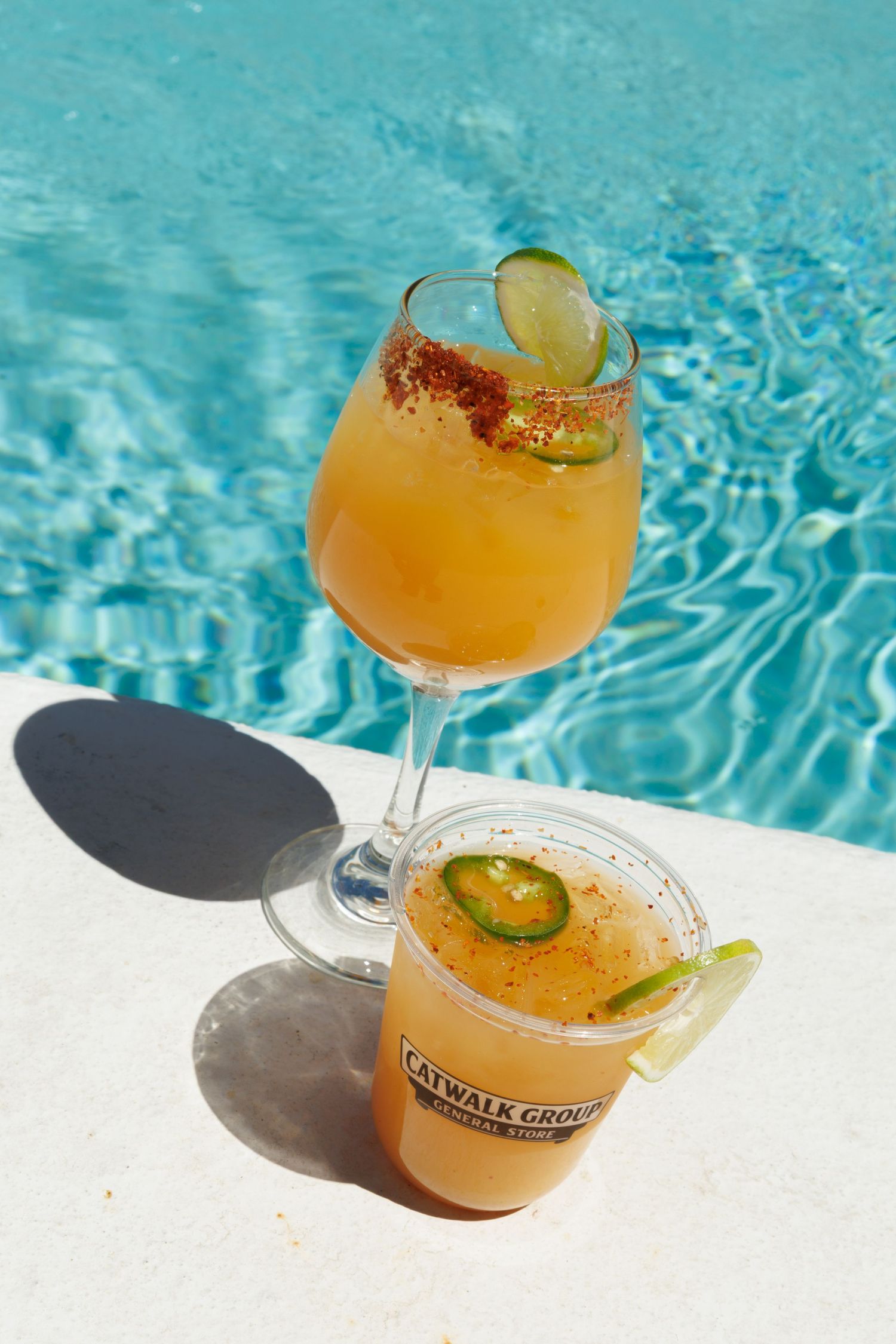 Two spicy mango cocktails garnished with lime and jalapeno served poolside by Catwalk Group.