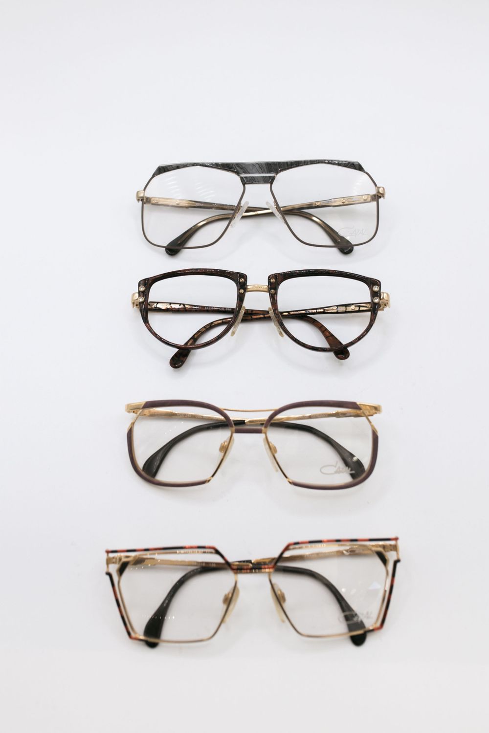 Collection of vintage eyeglass frames arranged in rows on white background.