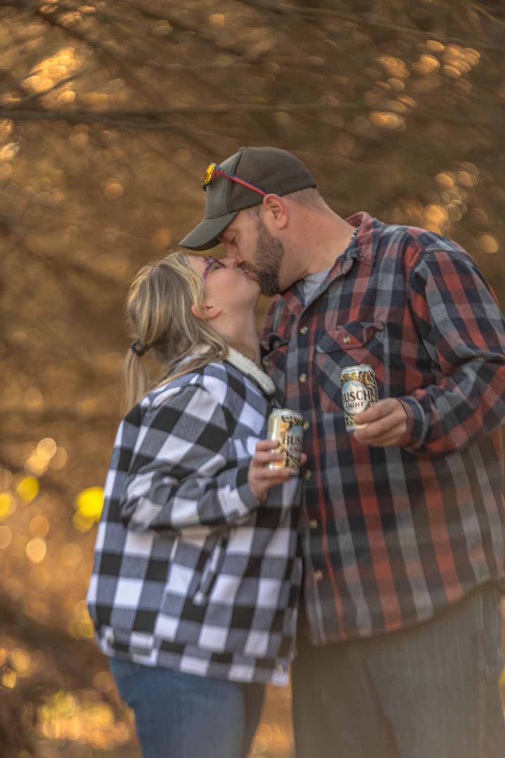 Couple in matching plaid shirts share intimate moment while holding beverages.