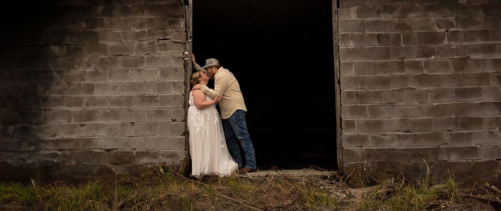 Wedding couple posing dramatically in doorway of rustic brick building.