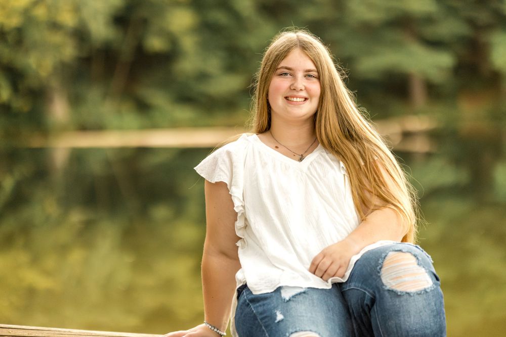 Casual summer portrait on fence wearing white t-shirt and distressed jeans.