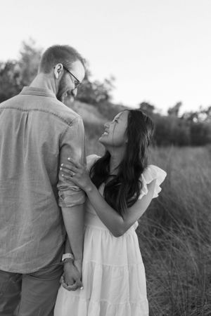 A romantic black and white portrait of a couple sharing an intimate moment together in a grassy field.