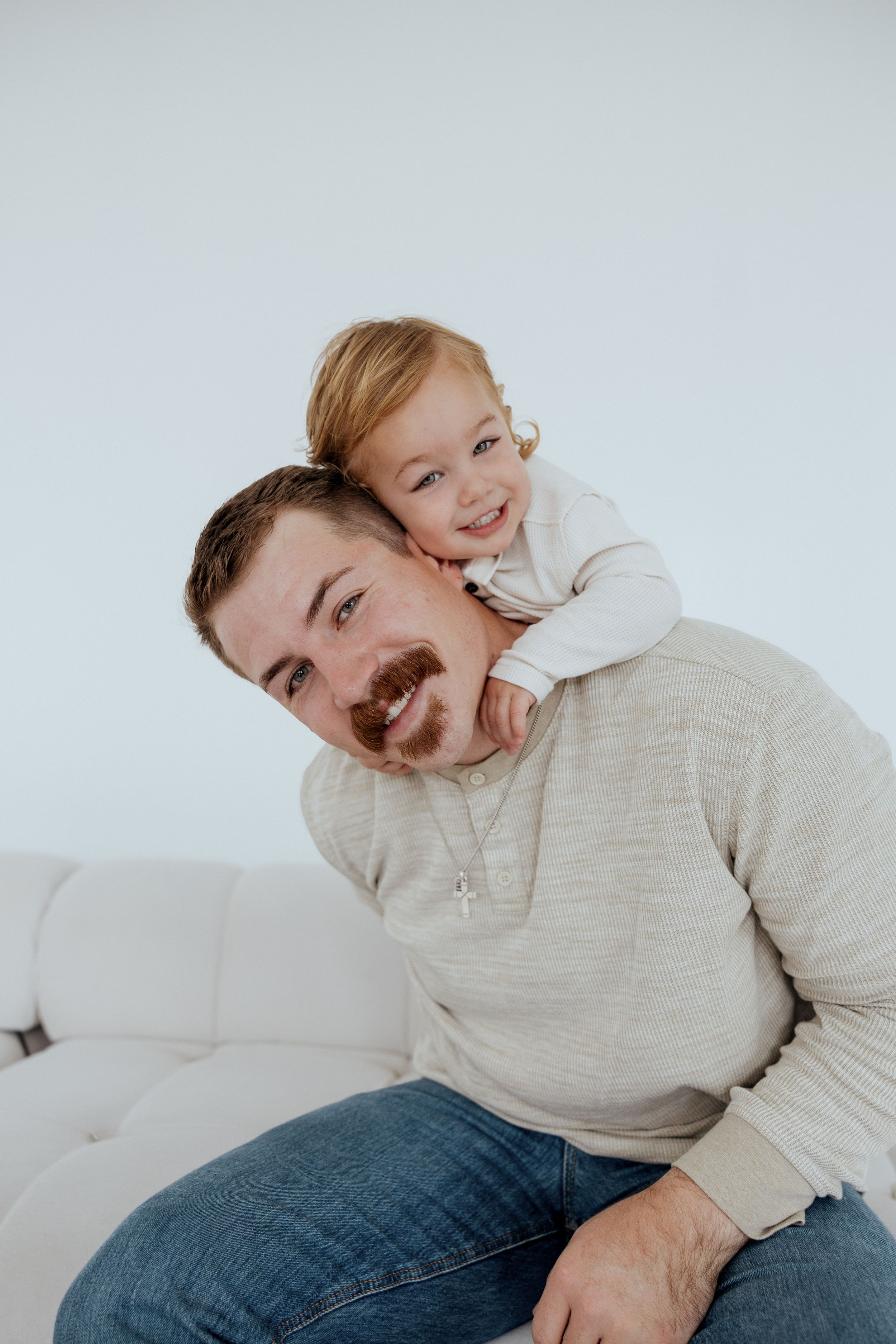 A playful moment shared together on a white couch, showing pure joy and connection.
