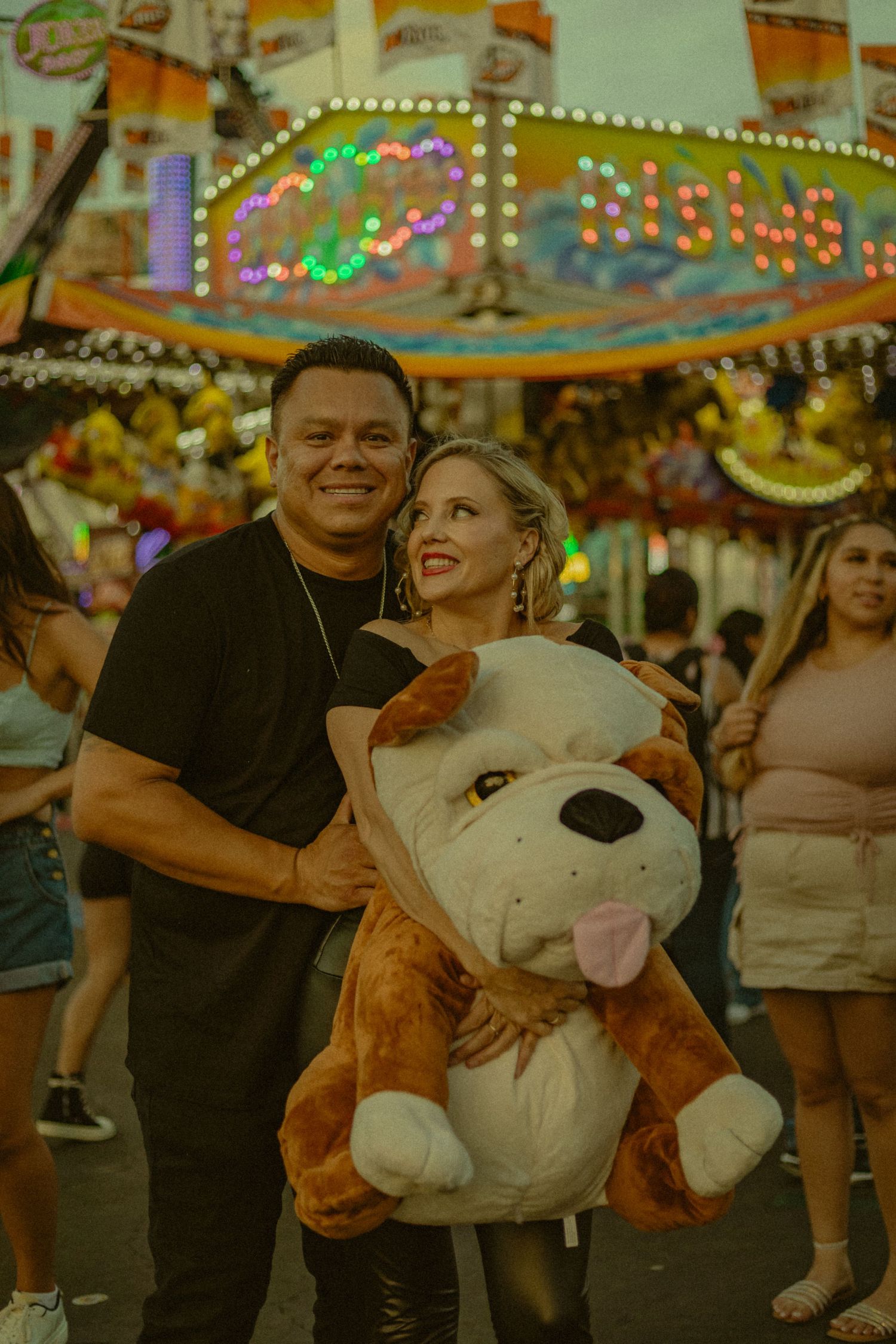 Sweet and romantic photoshoot in Orange County at the OC Fair grounds. Couple standing back to chest and holding their prize.