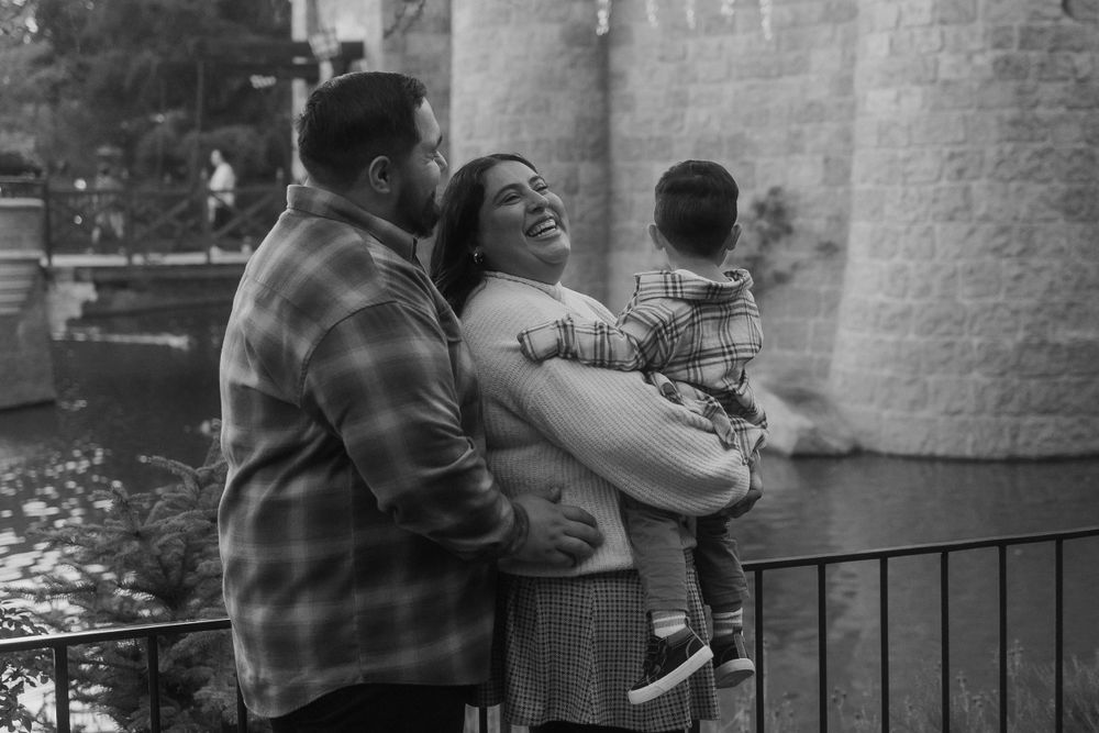 A tender family moment captured in black and white against stone architecture.