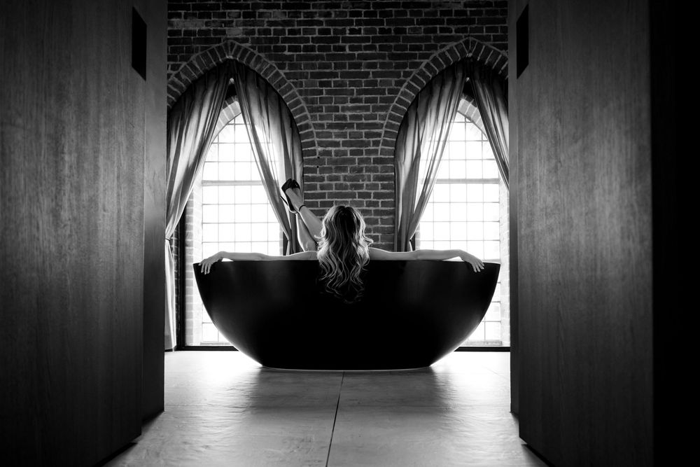 Dramatic black and white architectural interior with brick walls and stark window lighting creating moody silhouettes.