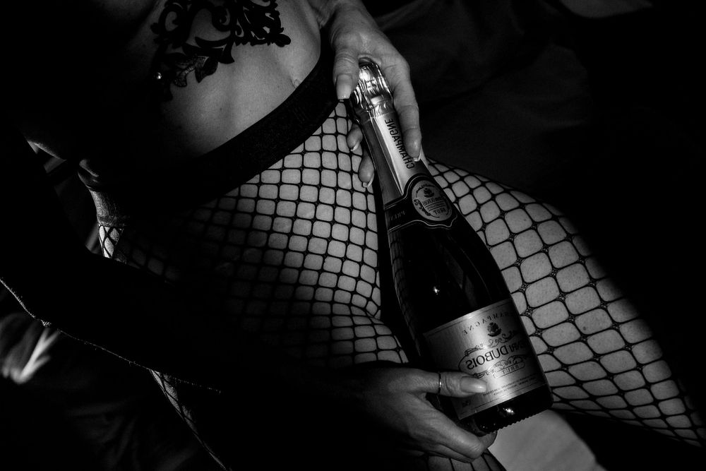 Black and white photo of fishnet stockings and champagne bottle.
