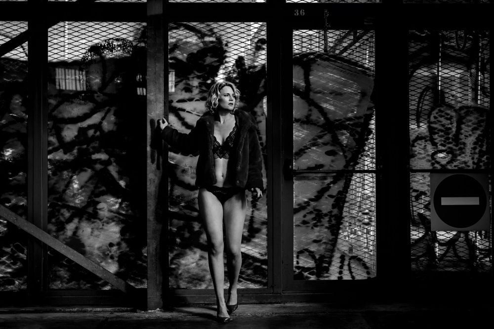 Silhouette of a dancer performing in front of a patterned window backdrop.