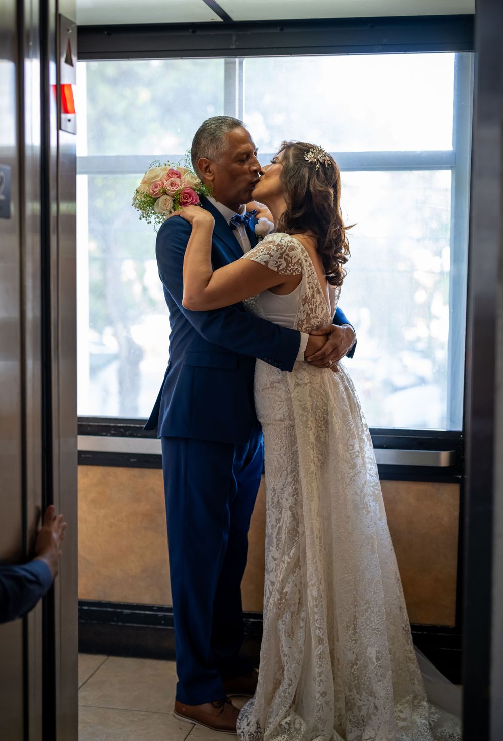 Couple sharing tender moment in sunlit room during wedding celebration.