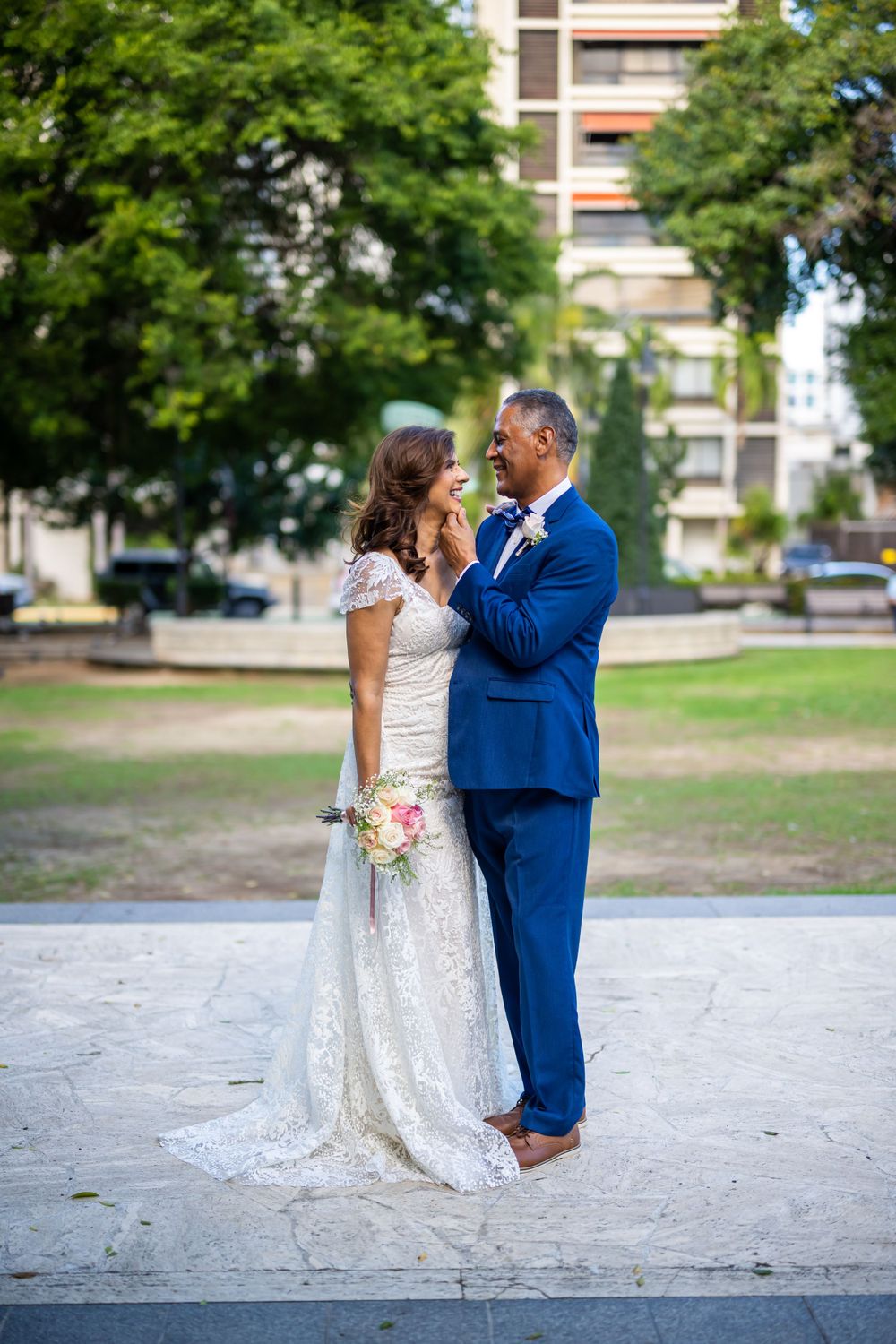 Romantic wedding portrait of couple dancing in urban park setting.