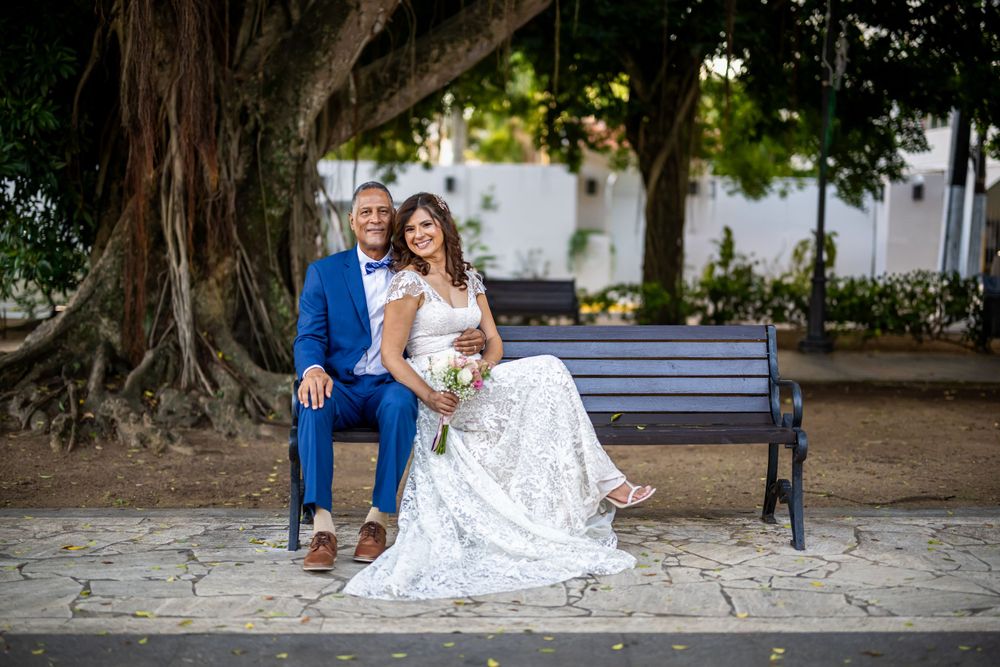 The newlyweds share an intimate moment under a large tree in a garden setting.
