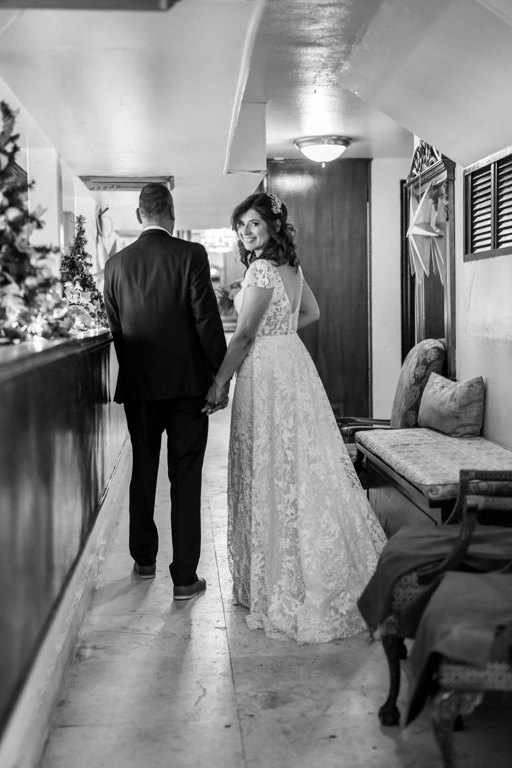 Black and white photos of a couple walking down a hallway in wedding attire.