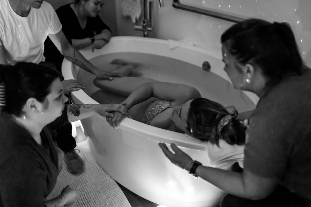 Black and white behind-the-scenes photo of milk bath maternity shoot preparation.