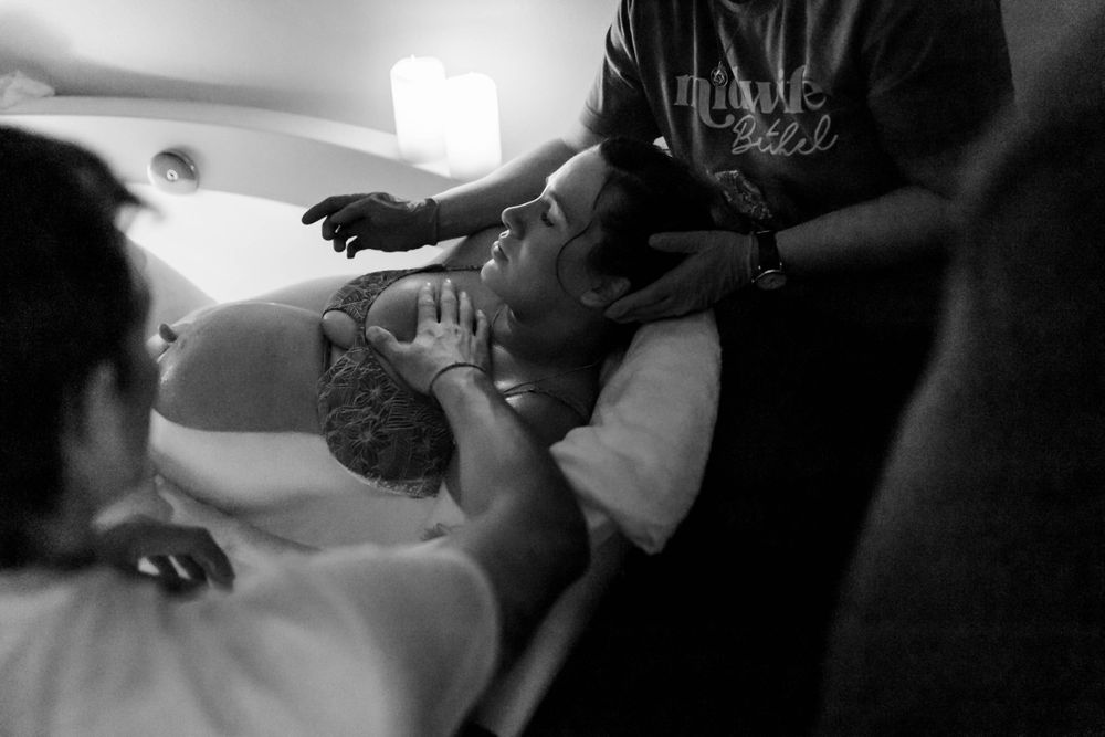 Black and white photo of a birth in progress showing medical professionals assisting during labor.