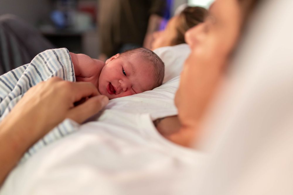 Close-up portrait of a peaceful newborn baby resting on white sheets.