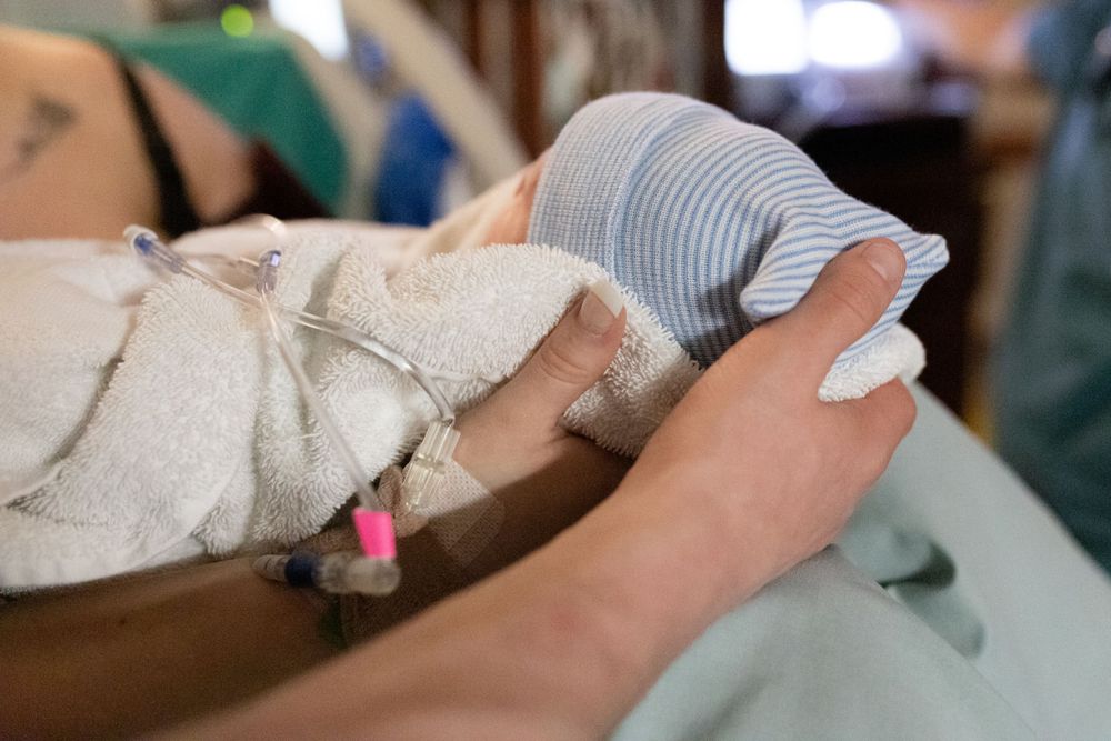 A close-up view of a tiny newborn baby wearing a blue knit hat.