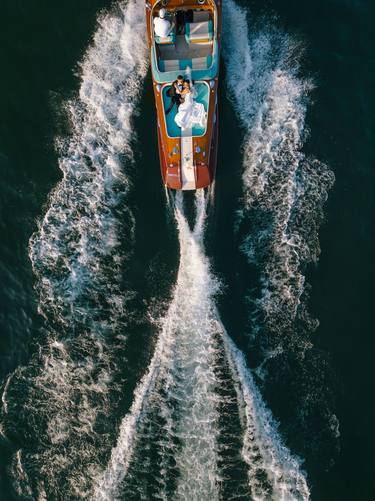 Stylish bride and groom wearing sunglasses share intimate moment on boat.