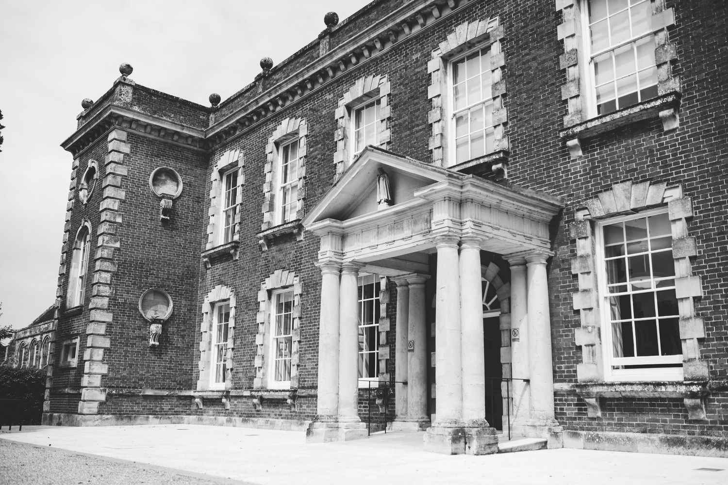 Historic brick building facade with white columns and ornate architectural details showing multiple entrance doorways.