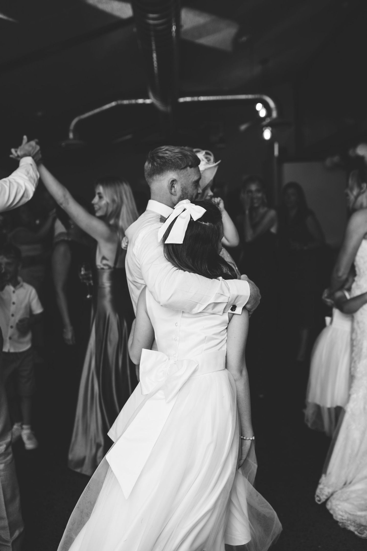 Black and white photo of wedding reception dancing in dimly lit venue.
