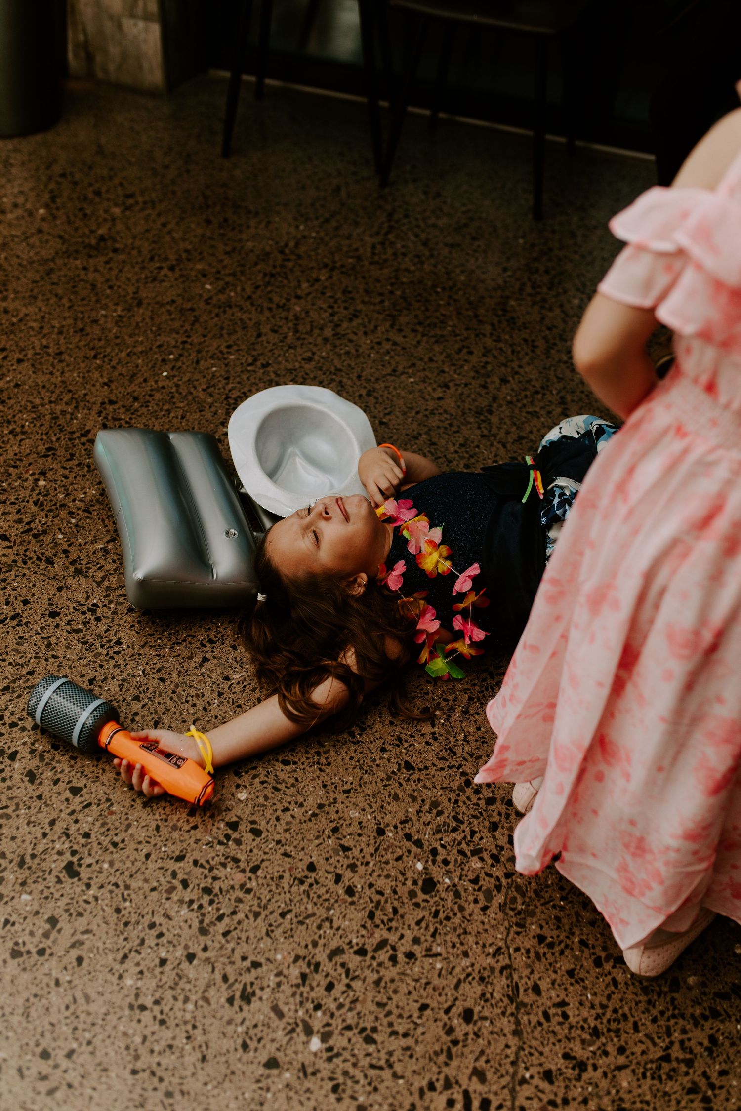 Person lying on dark floor with scattered flower petals and decorative elements.