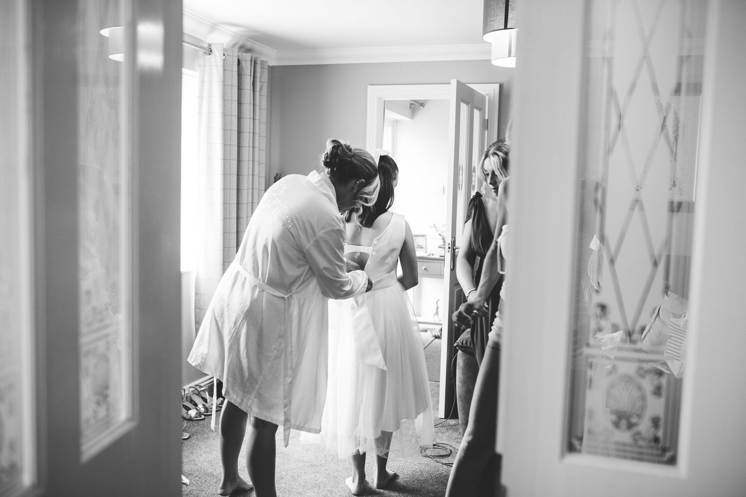 Artistic black and white wedding preparation photos in bright interior space.