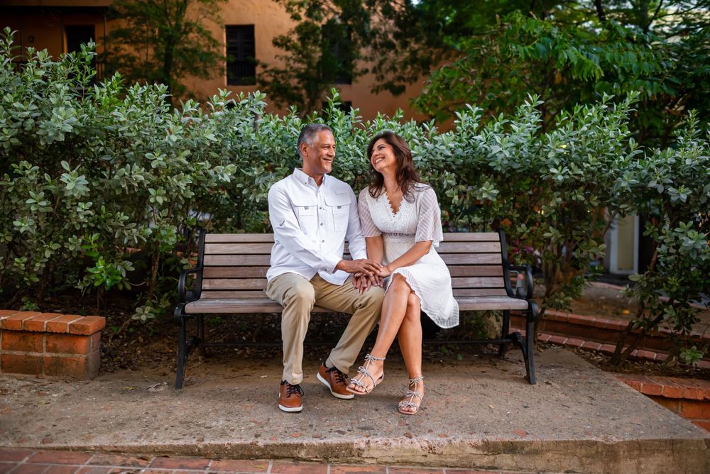 Couple sitting close together on park bench surrounded by lush greenery.