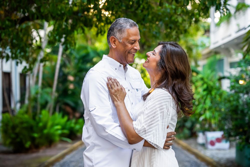 Romantic couple embracing in white outfits in a lush tropical garden setting.
