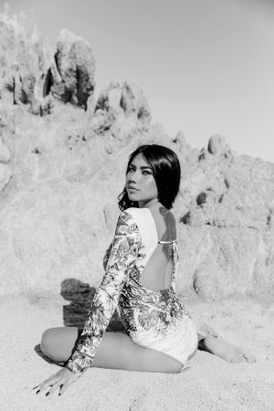 Black and white portrait on sandy beach with patterned long sleeve outfit.