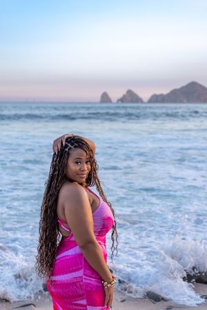Scenic beach photoshoot at sunset with crashing waves and mountain silhouettes in the background.