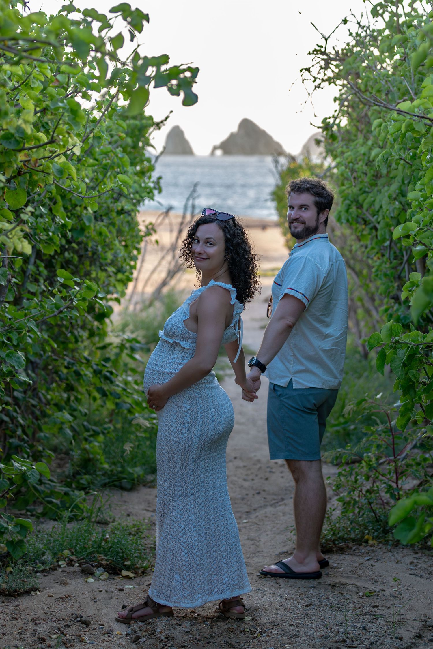 A couple shares a tender moment among green vines in a vineyard during sunset.