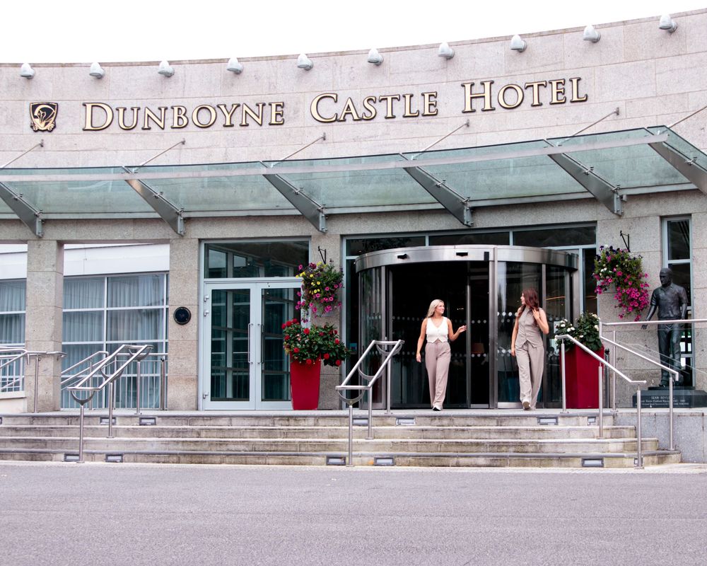 Exterior view of the Dunlorne Castle Hotel building with signage and hanging flower baskets.