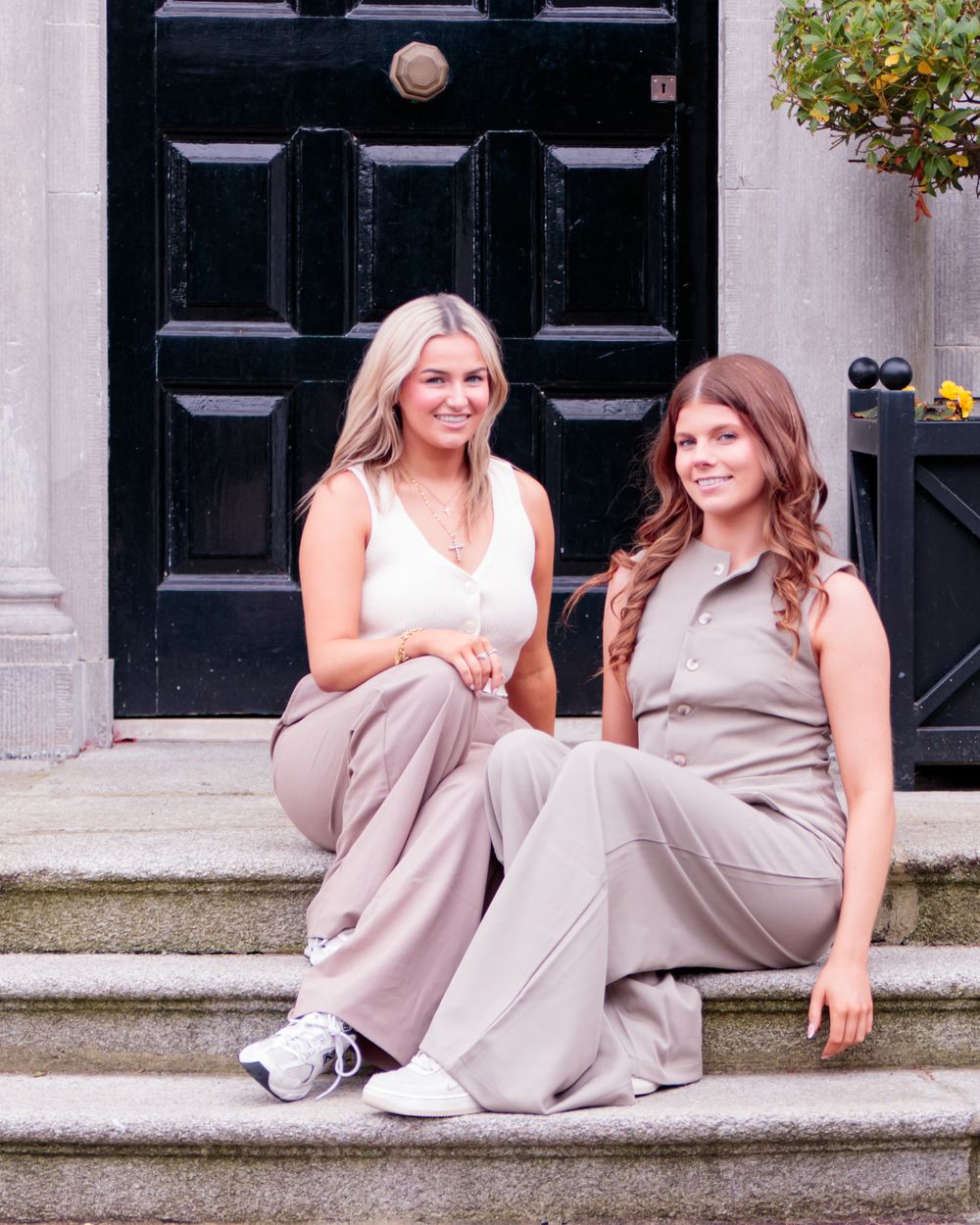 Group posing casually on stone steps in coordinated neutral-colored outfits.